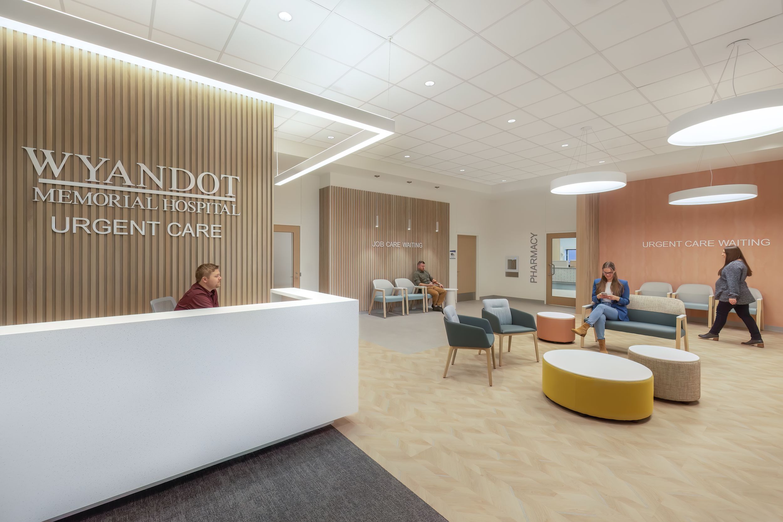 Minimalist commercial lobby space with wood paneling, drop ceiling, and modern seating arrangements.