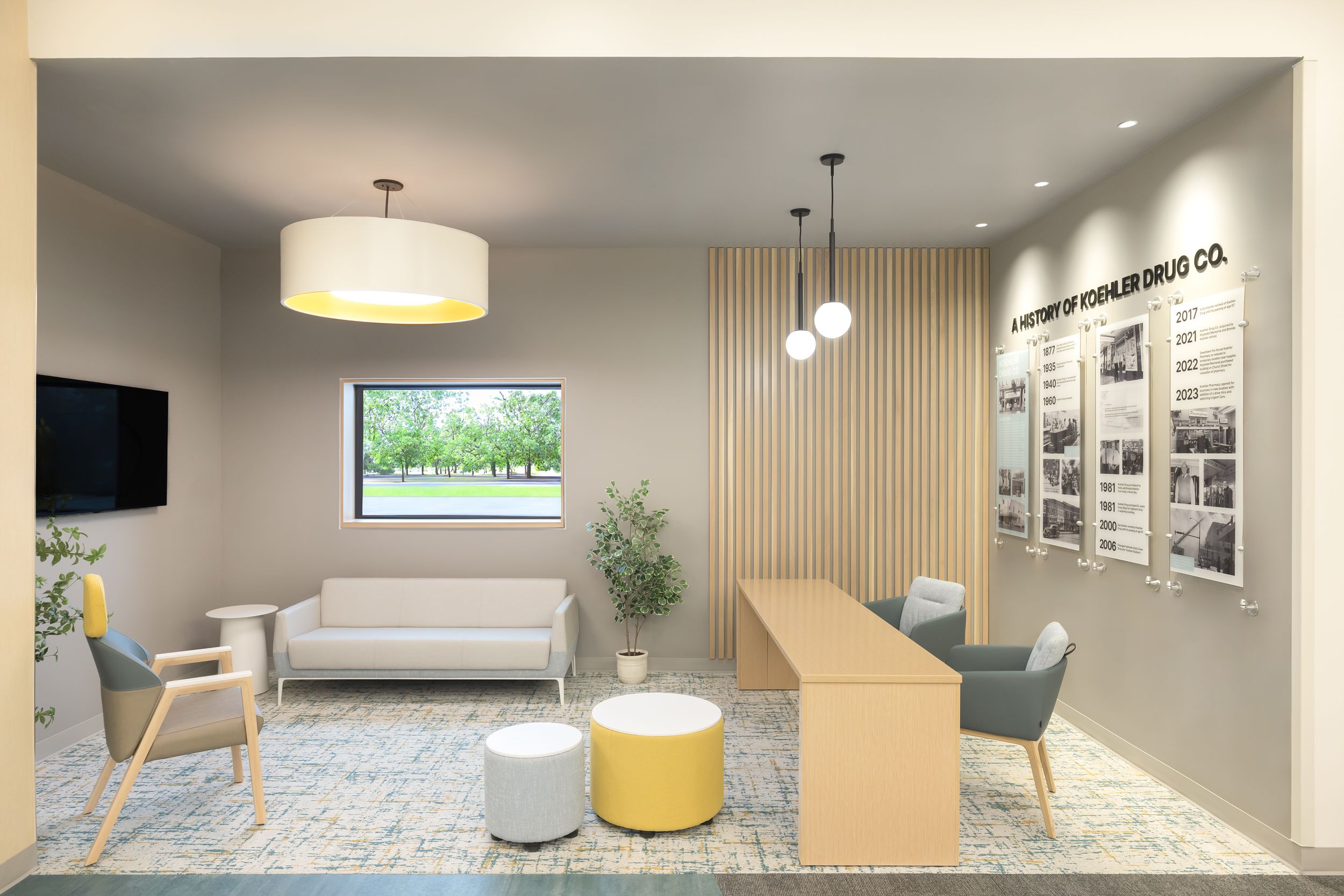 Modern office interior design featuring pendant lighting, wood accents, and comfortable seating areas with neutral color scheme.