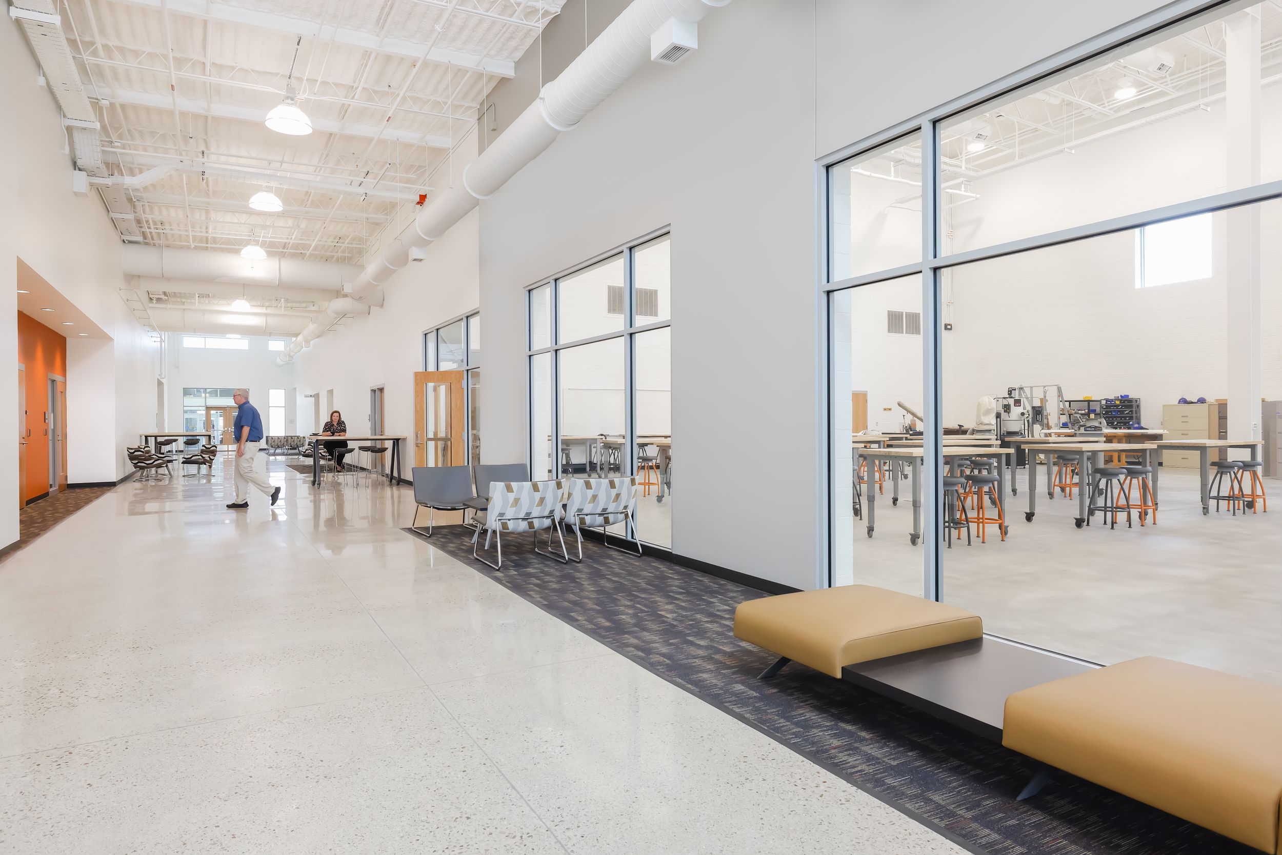 Modern industrial office space with exposed white ceiling, polished concrete floors, and large windows providing natural light.
