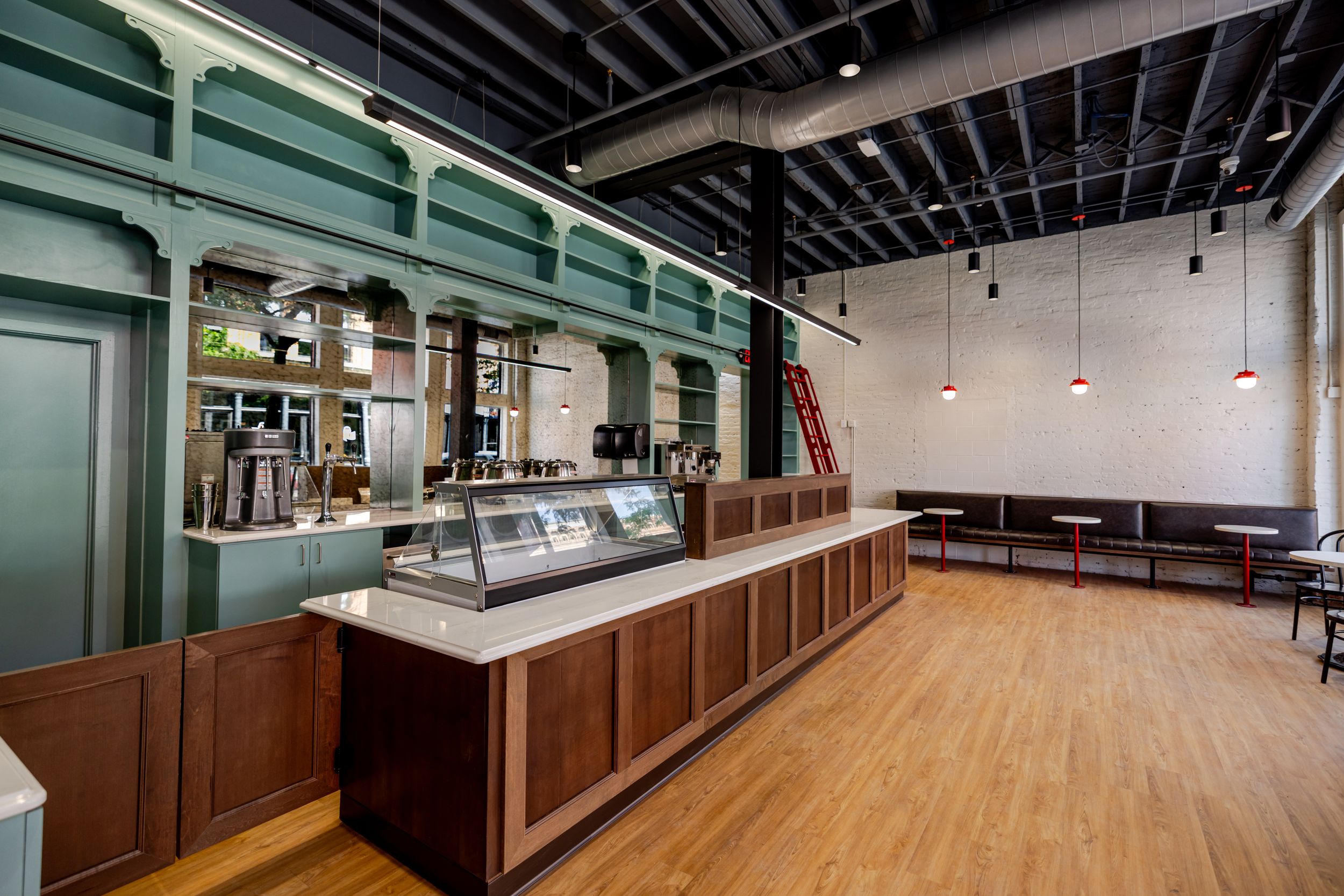 Modern commercial interior space with polished wood floors and industrial black ceiling features exposed ductwork.