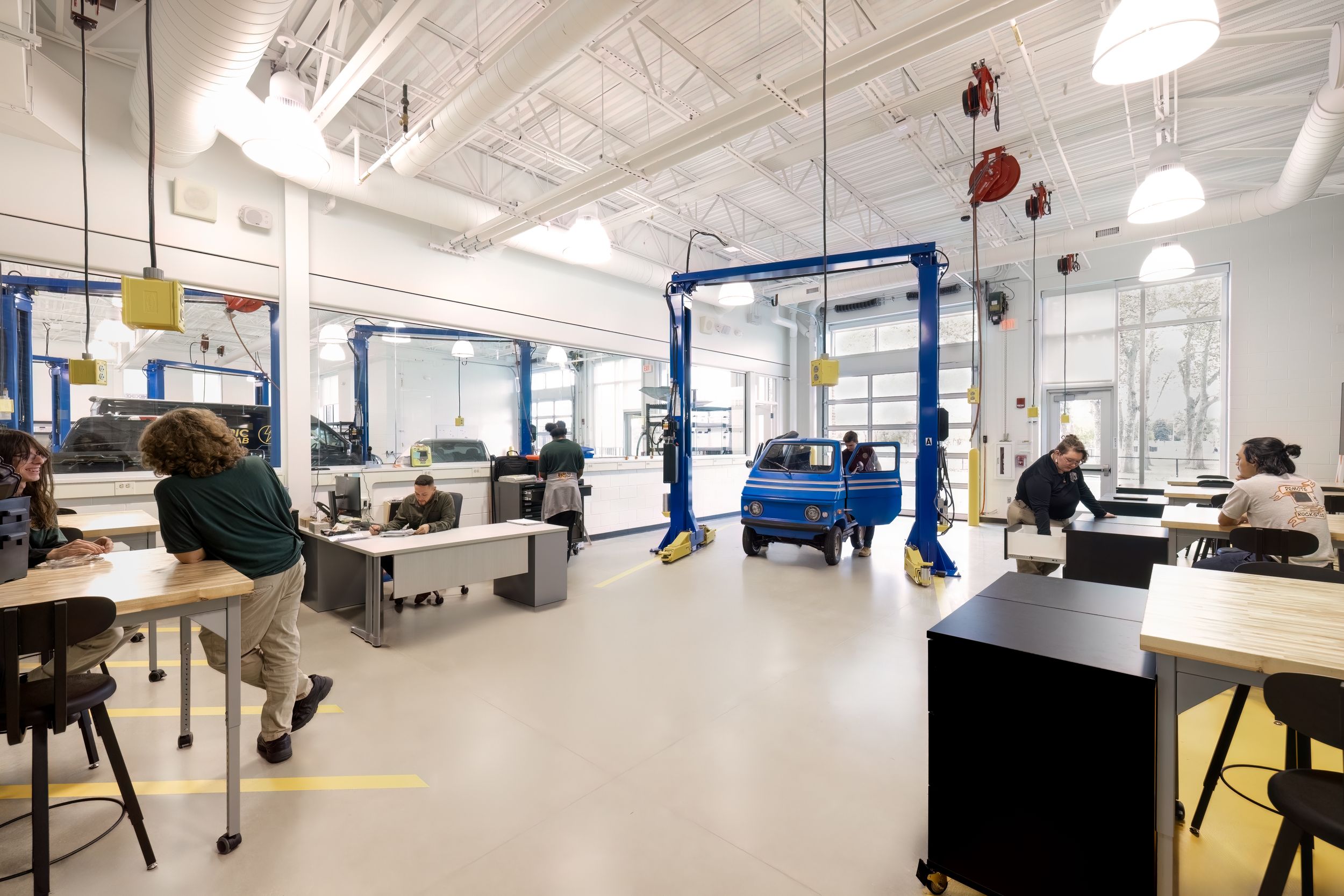Modern automotive service center interior with white walls, bright lighting, and multiple vehicle repair bays.