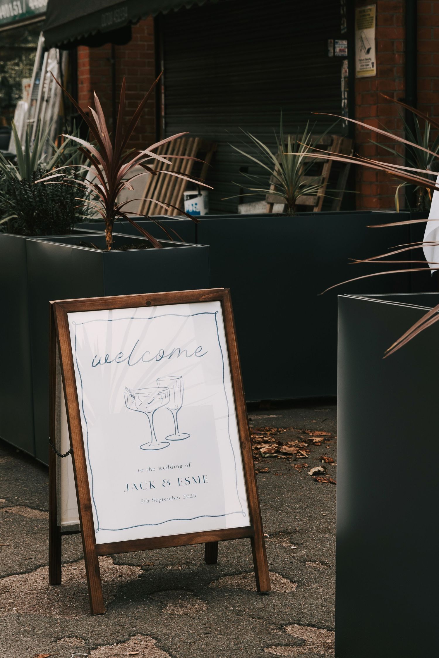 A series of wooden A-frame signs displaying welcome messages and cocktail illustrations for a wedding event.