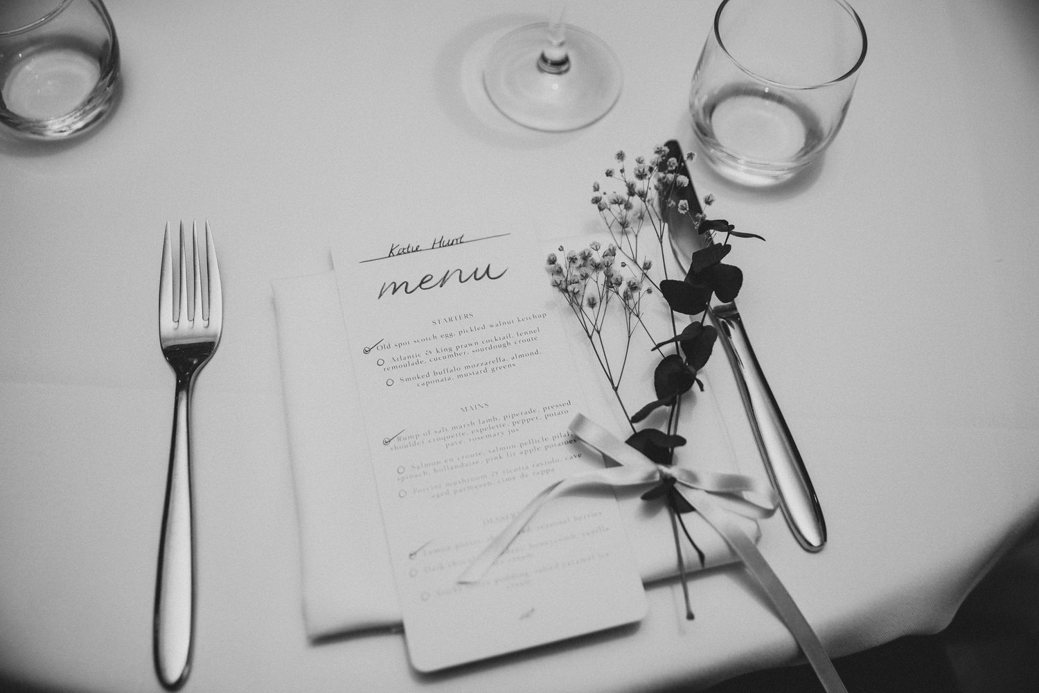 Elegant table setting with wine glasses and place settings in black and white.