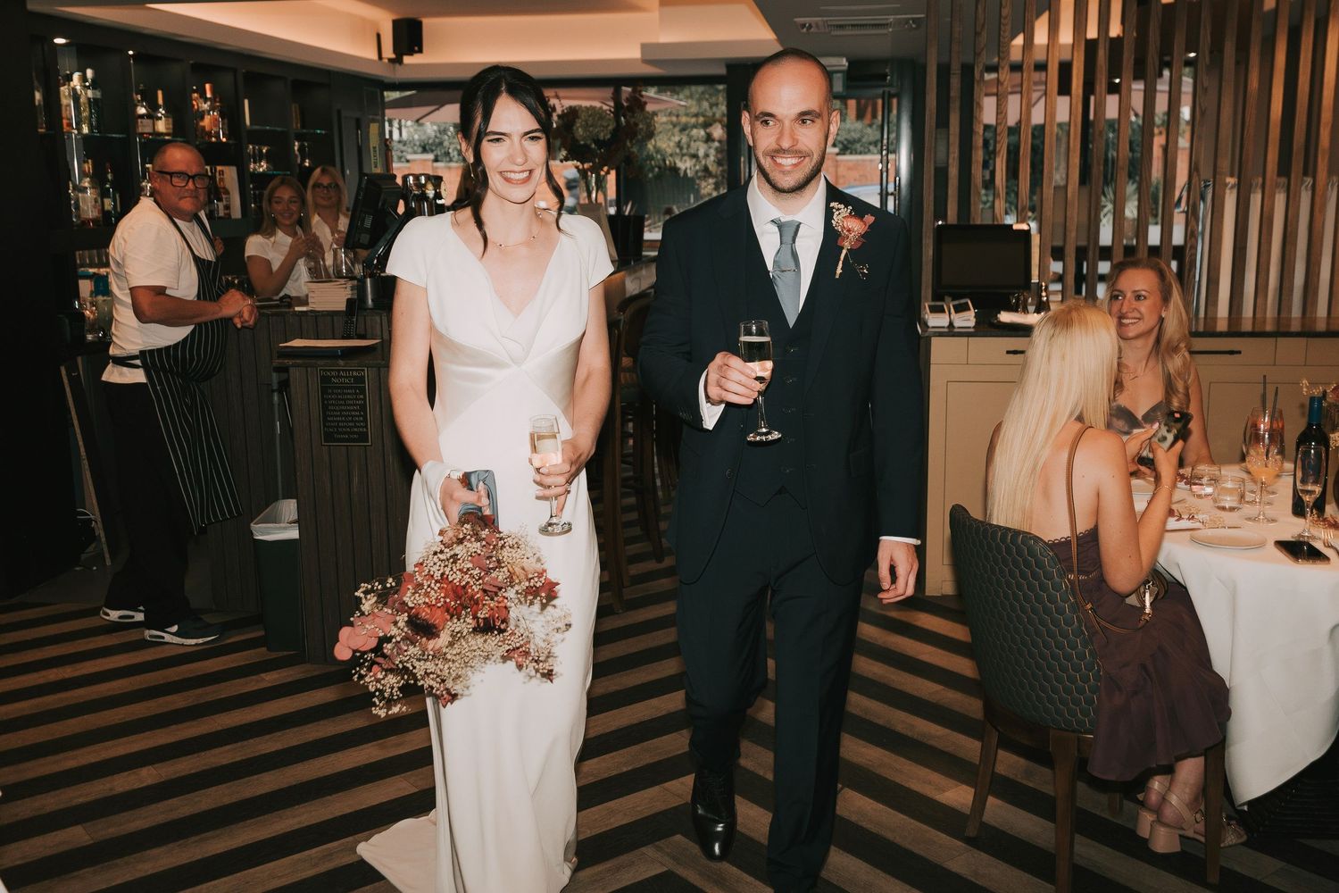 Wedding party walks down a wooden staircase in a dimly lit venue during an elegant reception celebration.