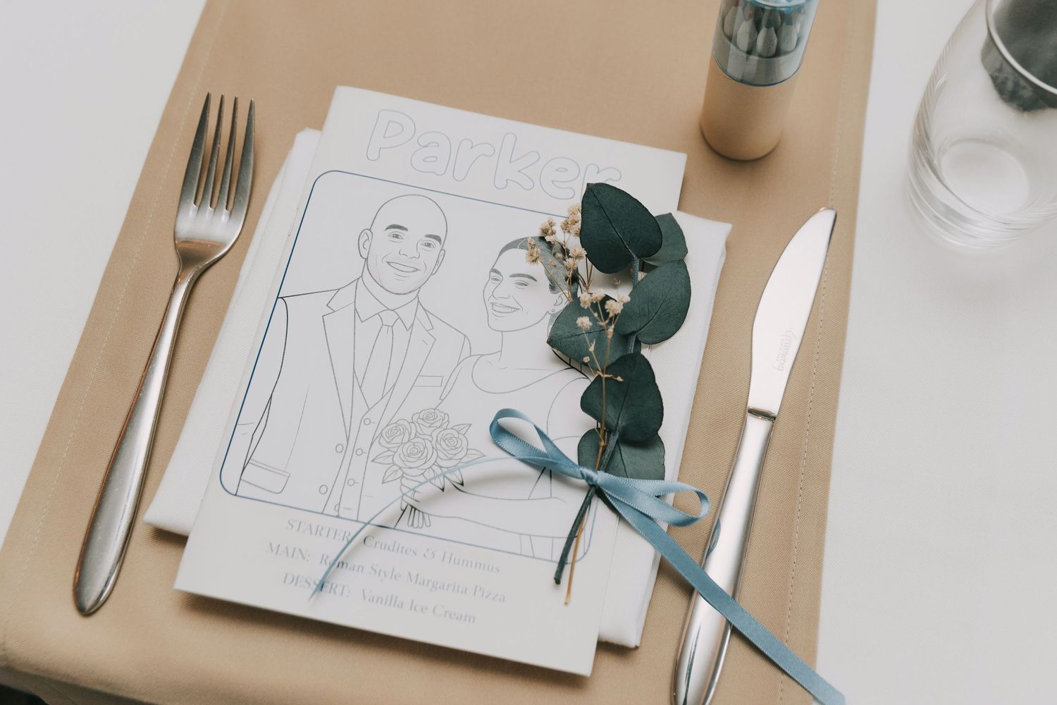 Place settings with menus, cutlery, and small floral decorations on white tablecloth.