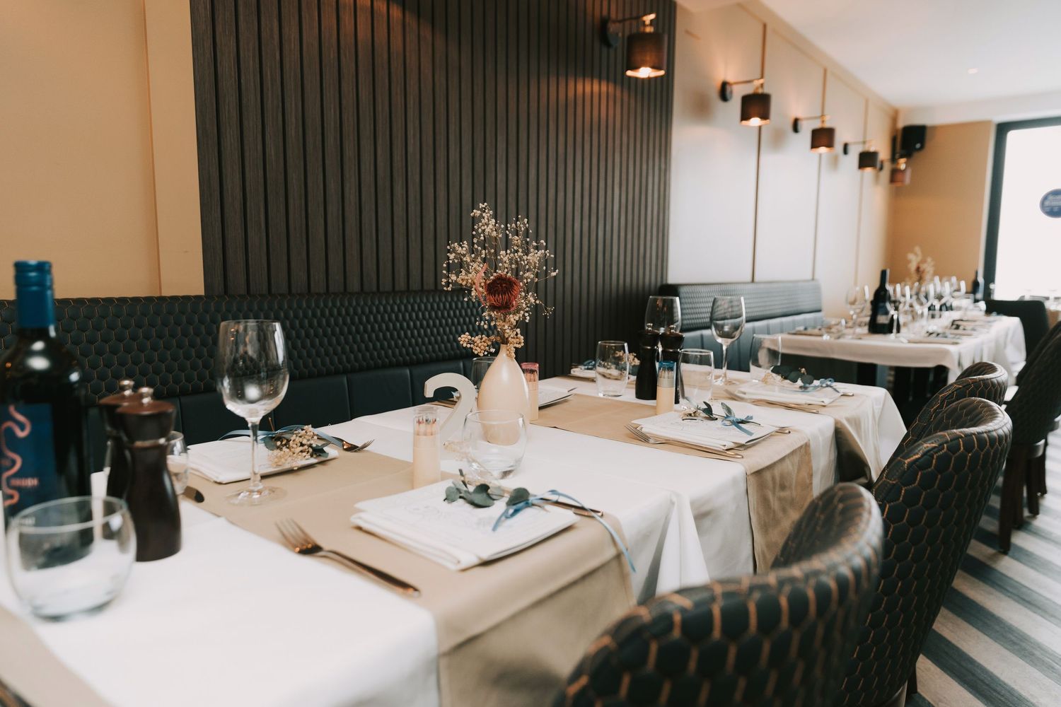 Modern restaurant interior with sleek white tables and chairs set against dark walls in minimalist design style.