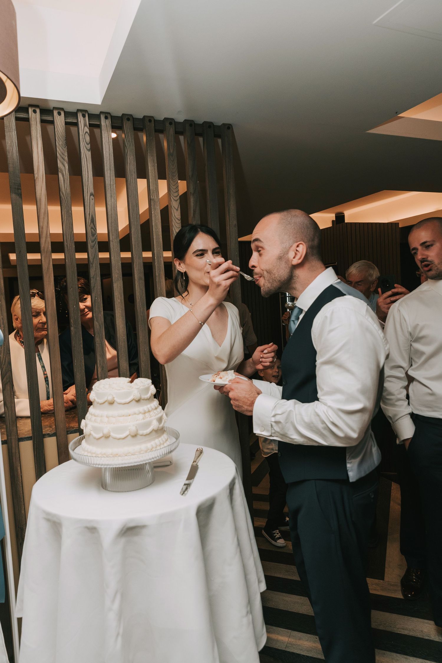 Newlyweds enjoy a fun cake-cutting moment together during their wedding reception celebration.