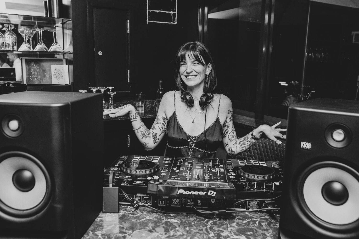 A DJ mixes music at a dimly lit club setup with professional equipment and monitors.