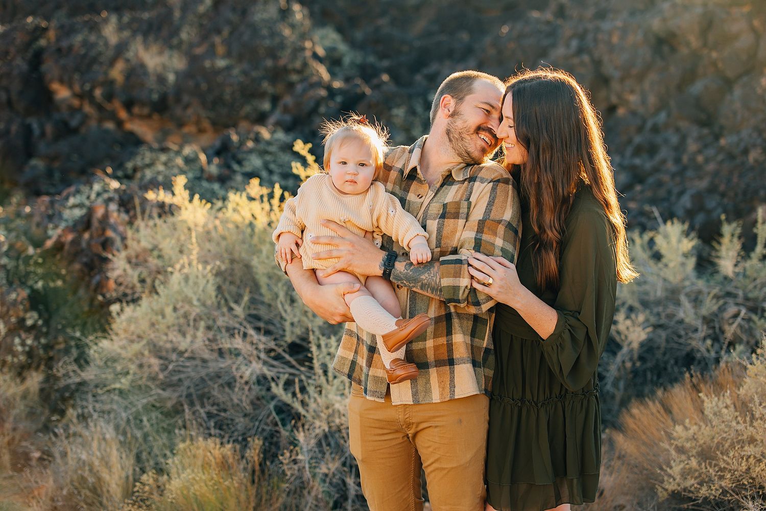 Family of three sharing a tender moment together in desert scenery during golden hour.