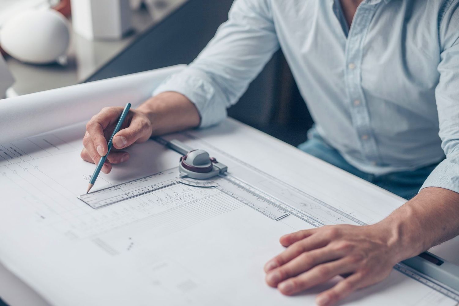 Architectural blueprint being drawn on white paper with drafting tools.