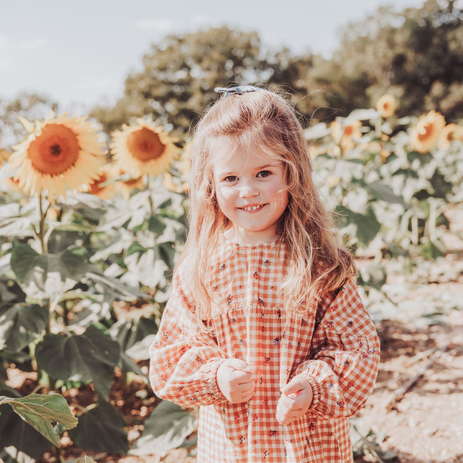 Young child standing in a sunflower field during a natural outdoor portrait session.