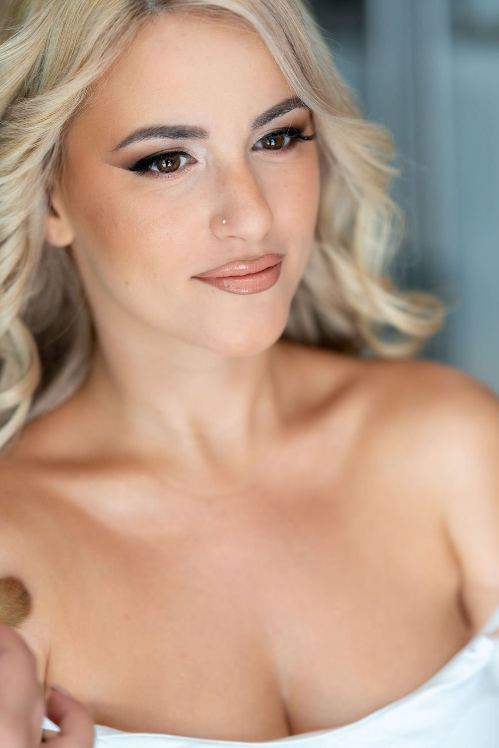 Glamorous beauty portrait with platinum blonde hair, smokey eye makeup, and white strapless top against blue backdropWedding Bride and Groom