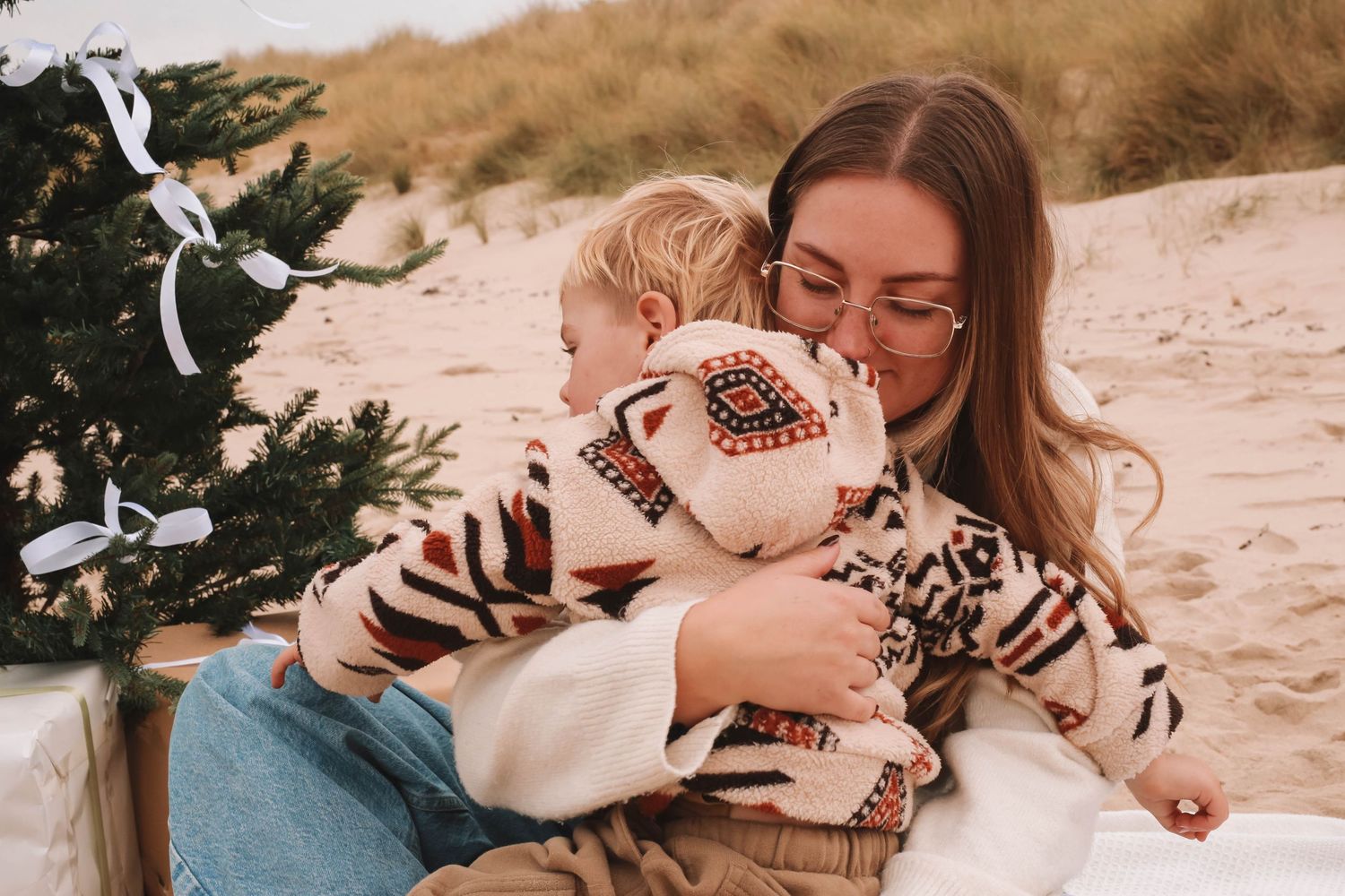 A parent and child share joyful moments together while playing on a sandy beach at sunset.