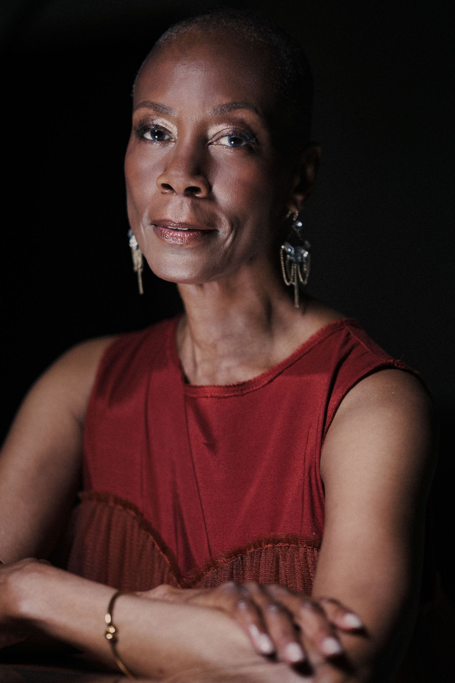 Close-up portrait with warm lighting showing gentle smile in red sleeveless top.