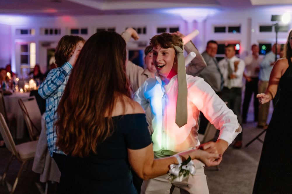 Wedding guests dancing and celebrating on a lively dance floor with colorful lights.