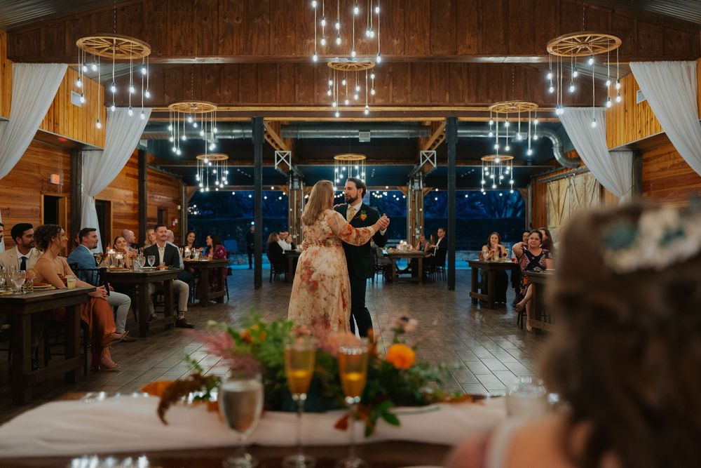 Wedding reception venue with rustic wooden beams and twinkling string lights creating a warm, romantic atmosphere.