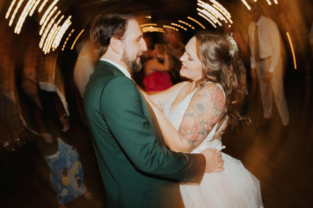A bride and groom share their first dance at their wedding reception in a warmly lit ballroom.
