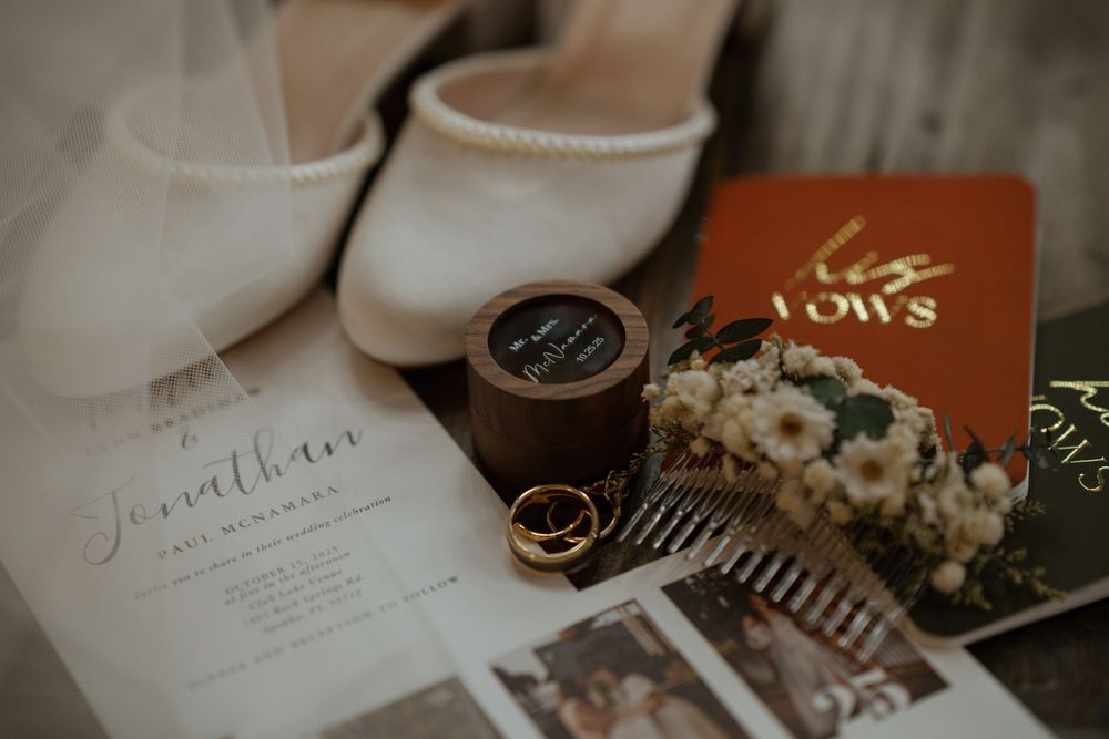 Wedding details including rings, invitations, flowers and decor arranged on a neutral surface.