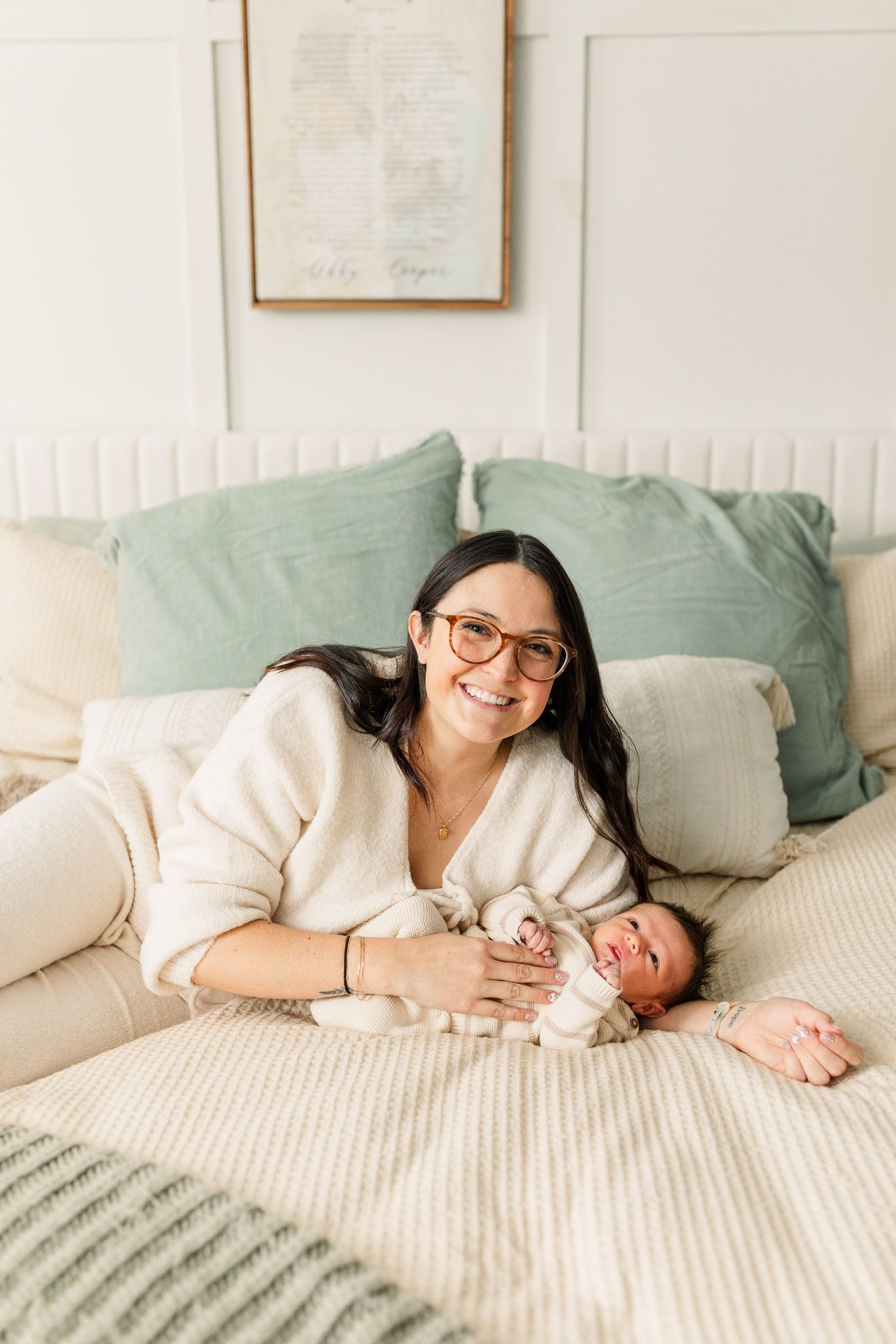 Mom holding baby while laying in bed and smiling