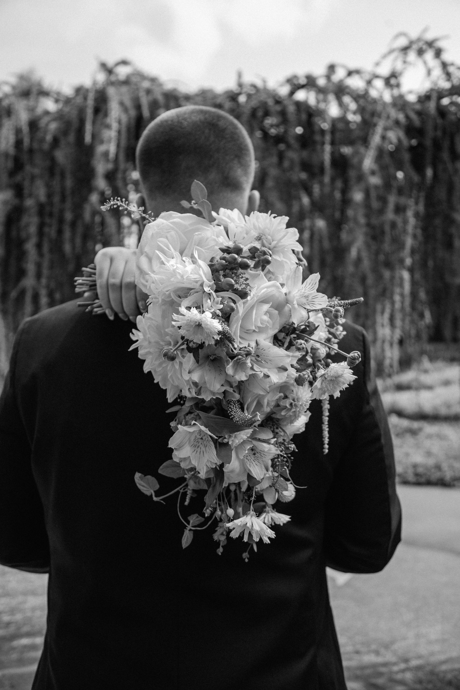 Wedding vows books in black and white marble designs with gold lettering alongside brass candlesticks and white flowers.