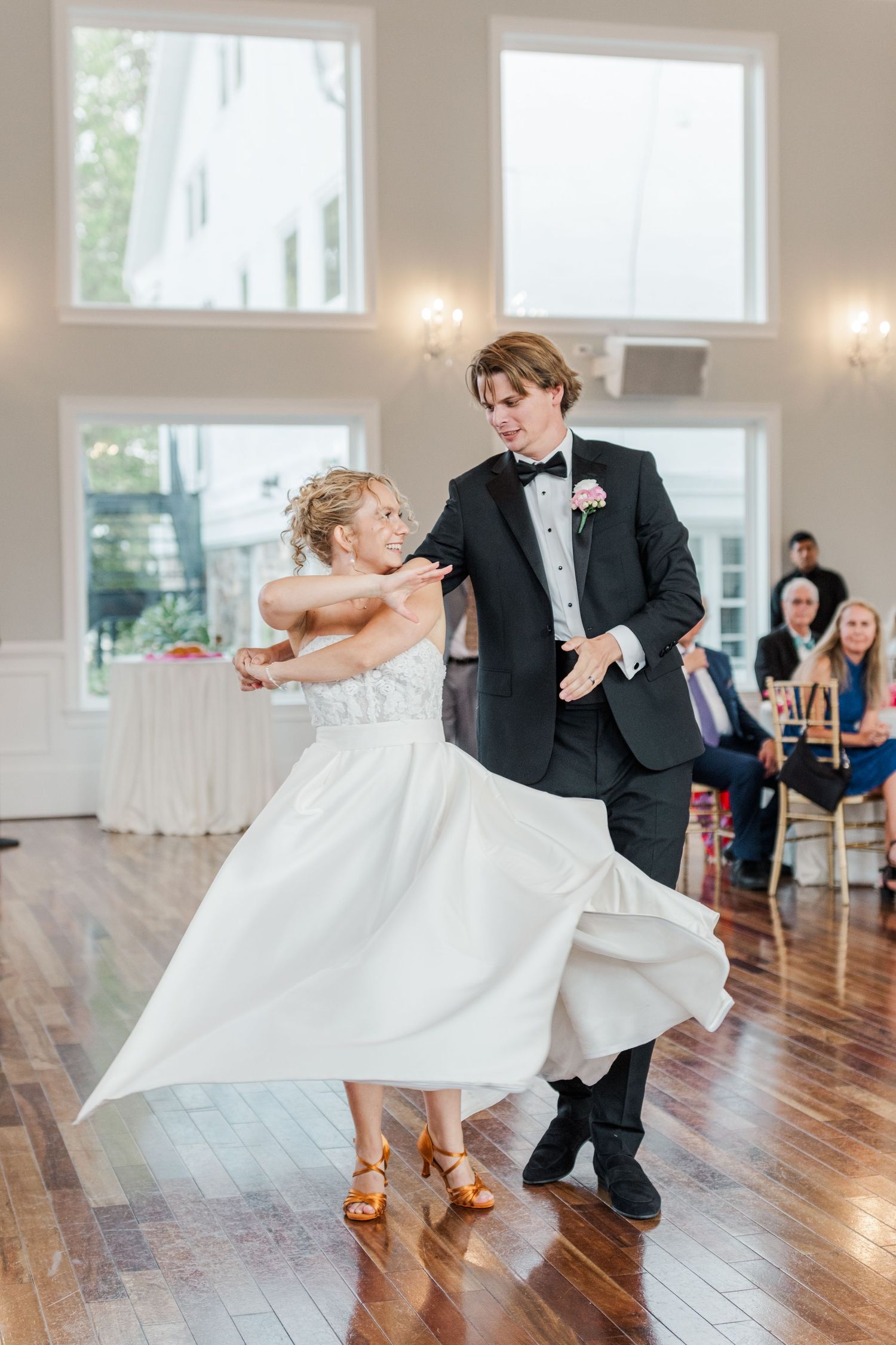 Couple performs an energetic dance move on a polished hardwood floor at their wedding reception.