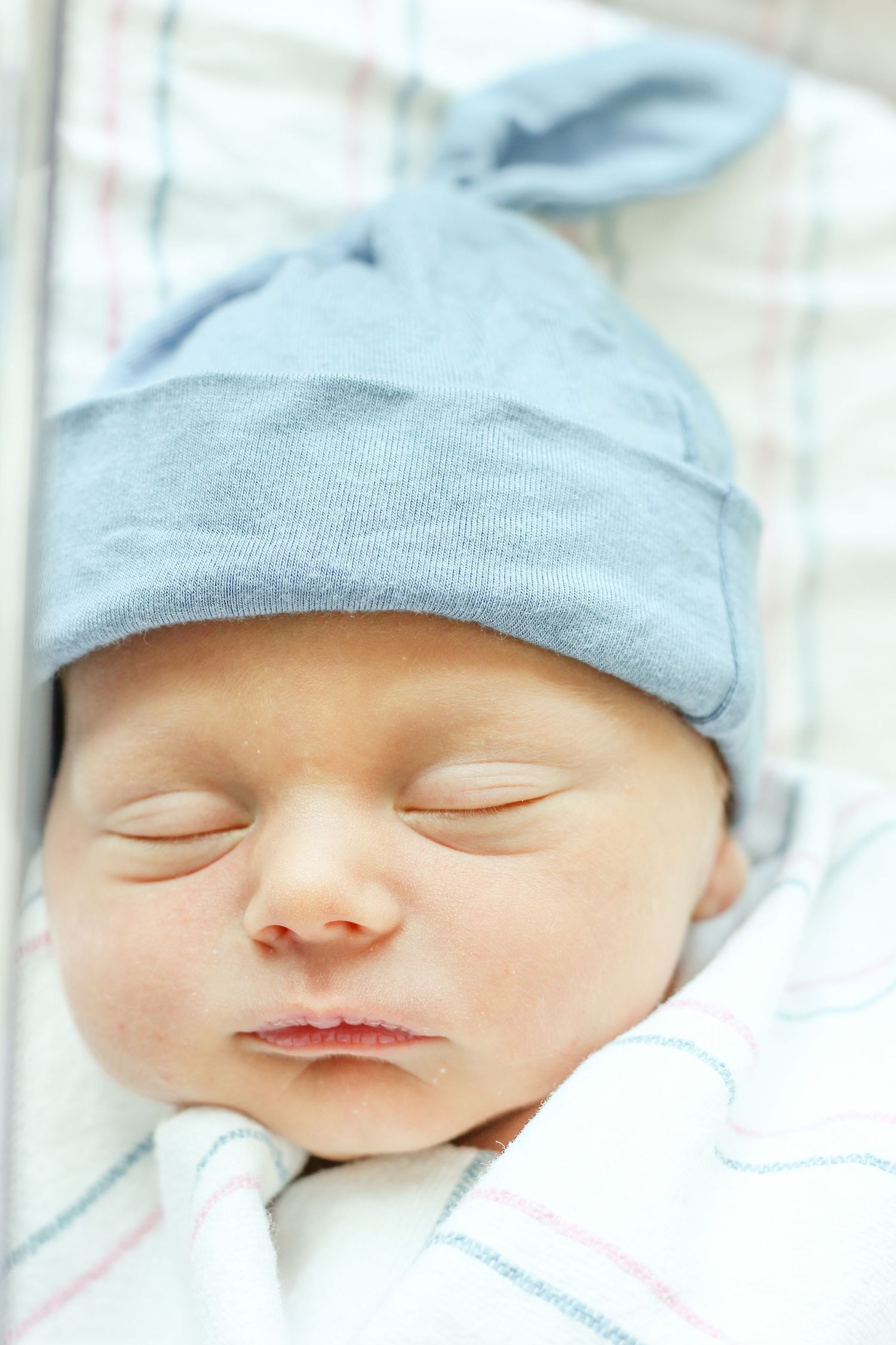 Cloise up picture of newborn baby swaddled in a blanket in hospital crib