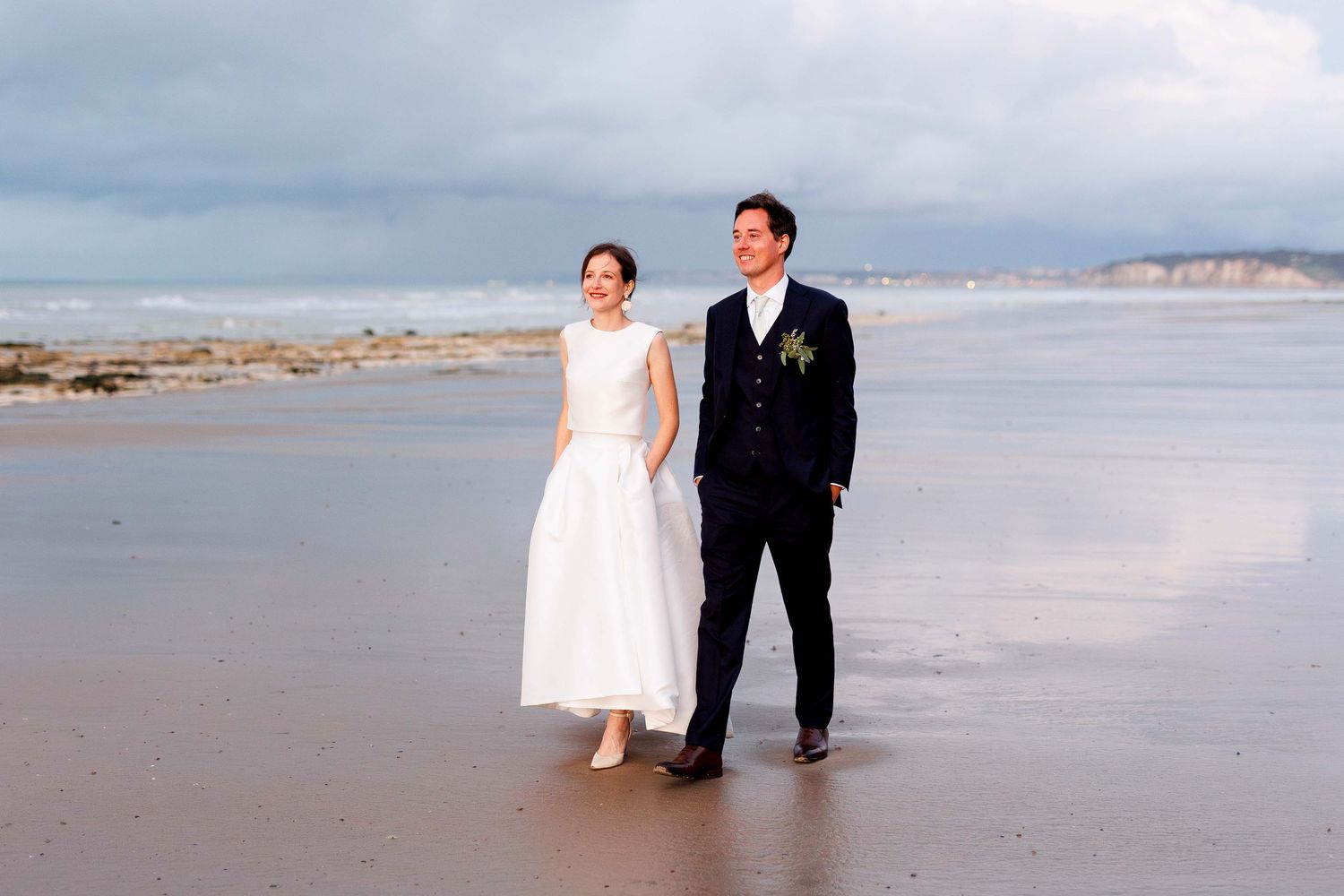 Wedding couple takes romantic photos along a scenic beach shoreline.