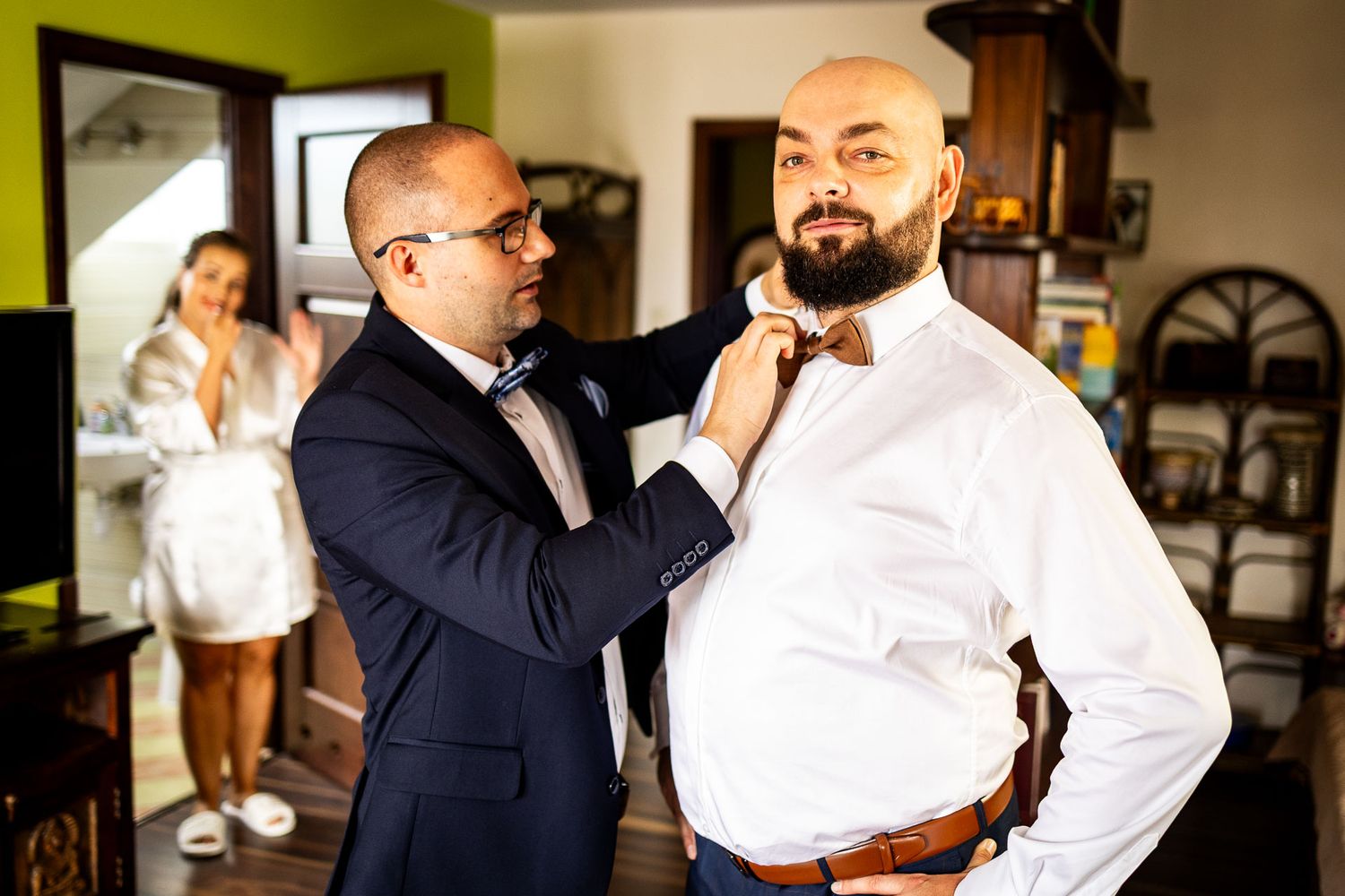 Wedding party members in navy suits adjusting their ties and accessories.