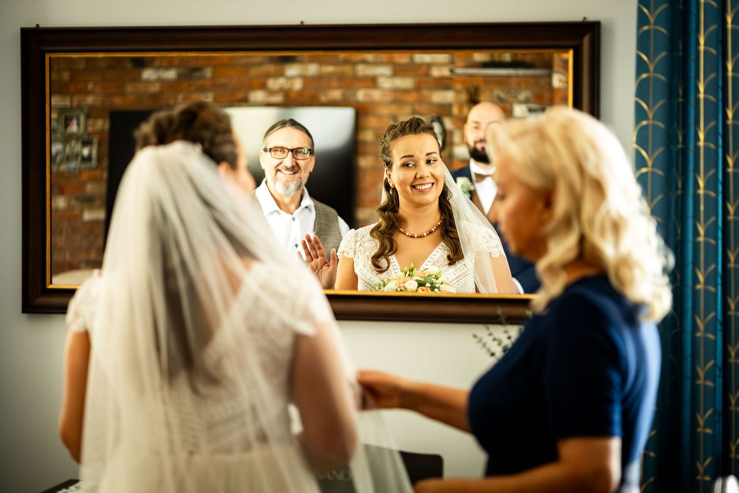 Wedding preparation scene reflected in mirror with exposed brick wall.
