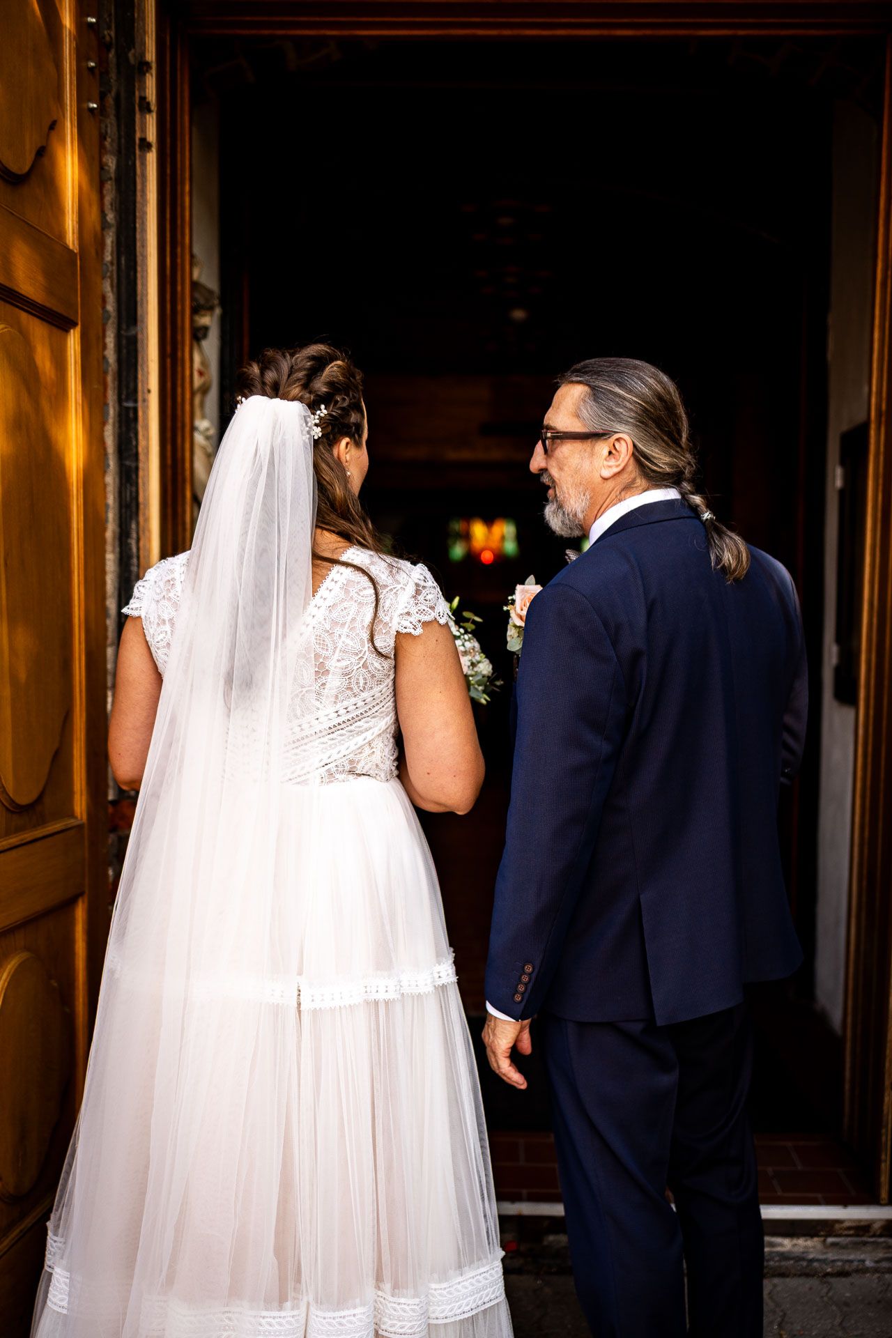 Wedding party entering dimly lit venue through wooden doorway.