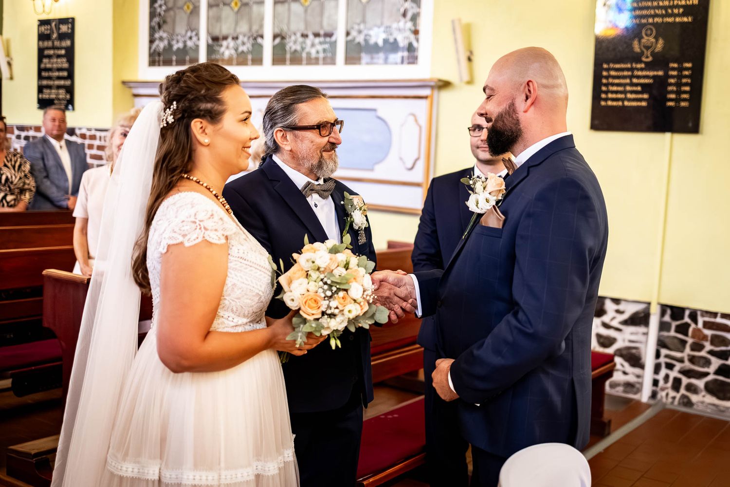 Wedding ceremony taking place in traditional church setting with yellow walls.