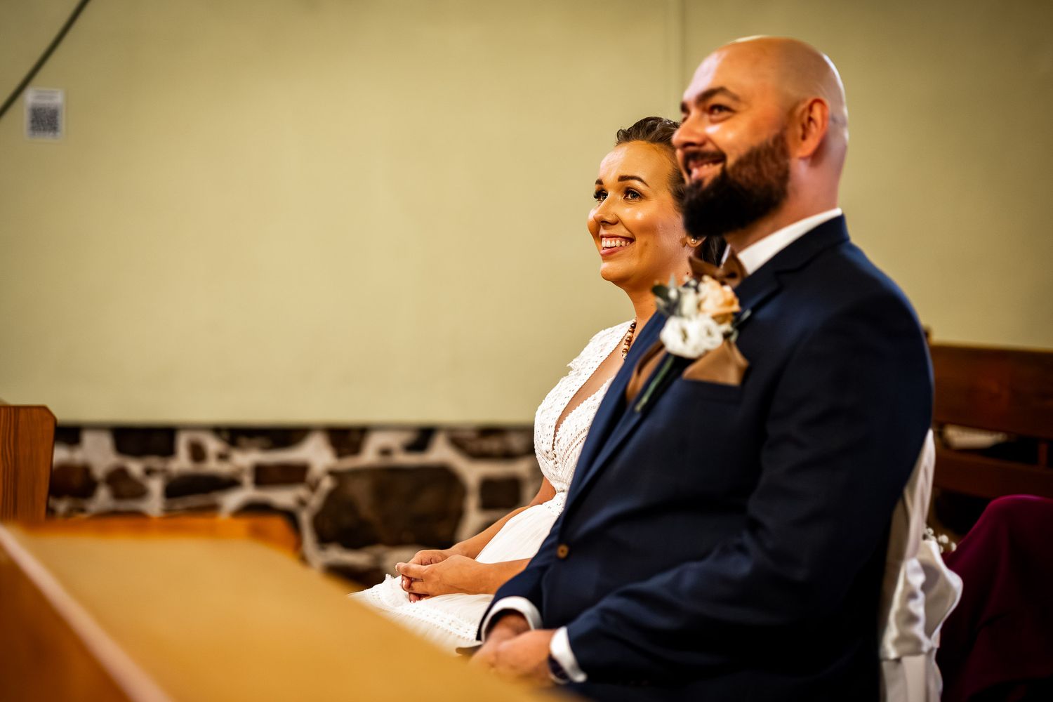 A couple shares a joyful moment during their wedding ceremony in a warmly lit church.