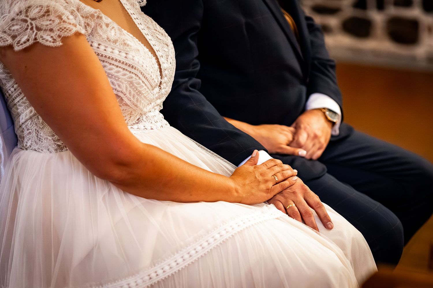 Wedding ceremony details showing elegant white dress and formal attire in church setting.