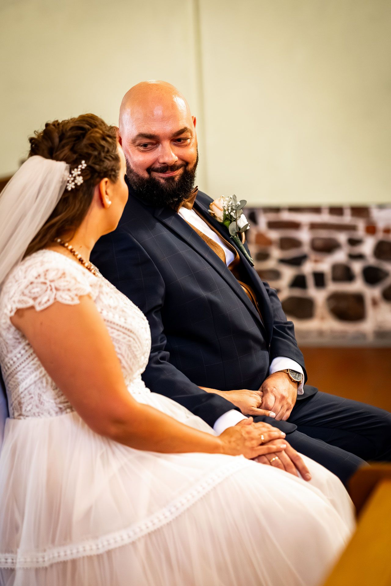 A couple shares an intimate moment during their wedding ceremony while seated together.