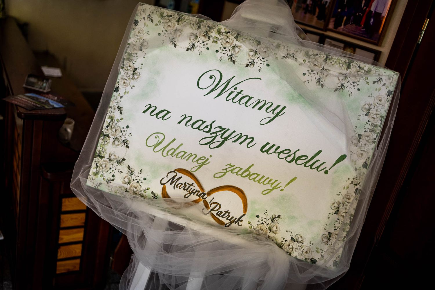 Wedding rings displayed on a decorative sign with floral designs.