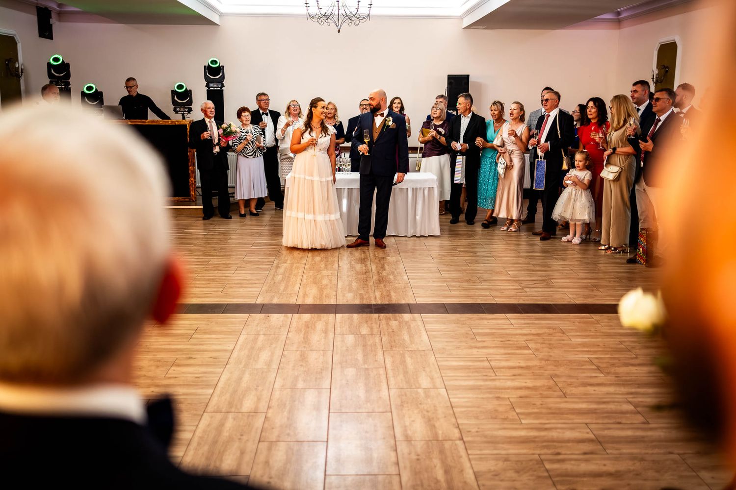 Wedding guests lined up on a dance floor during reception festivities.