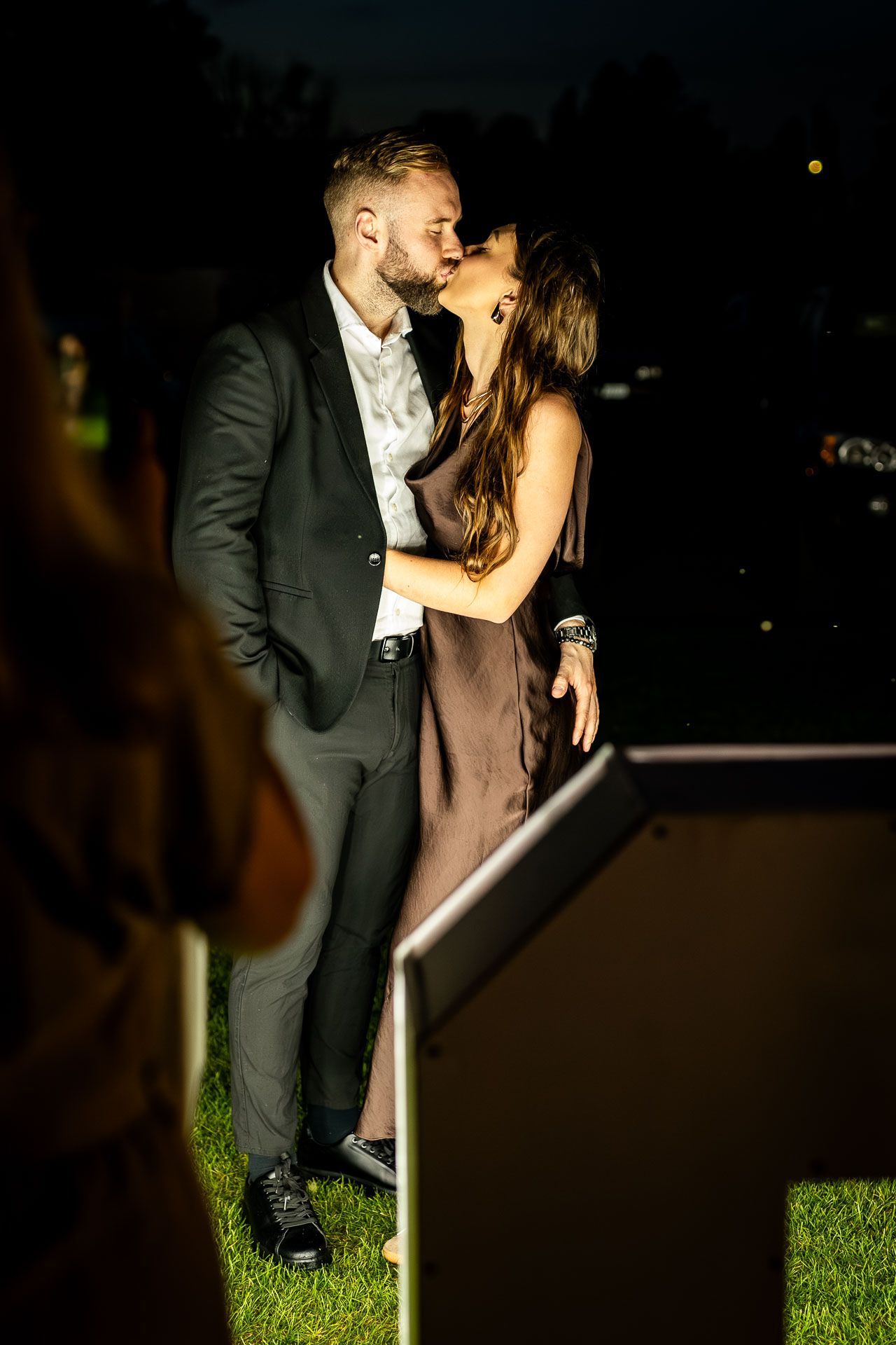 Romantic nighttime dance captured in dramatic lighting on grass.