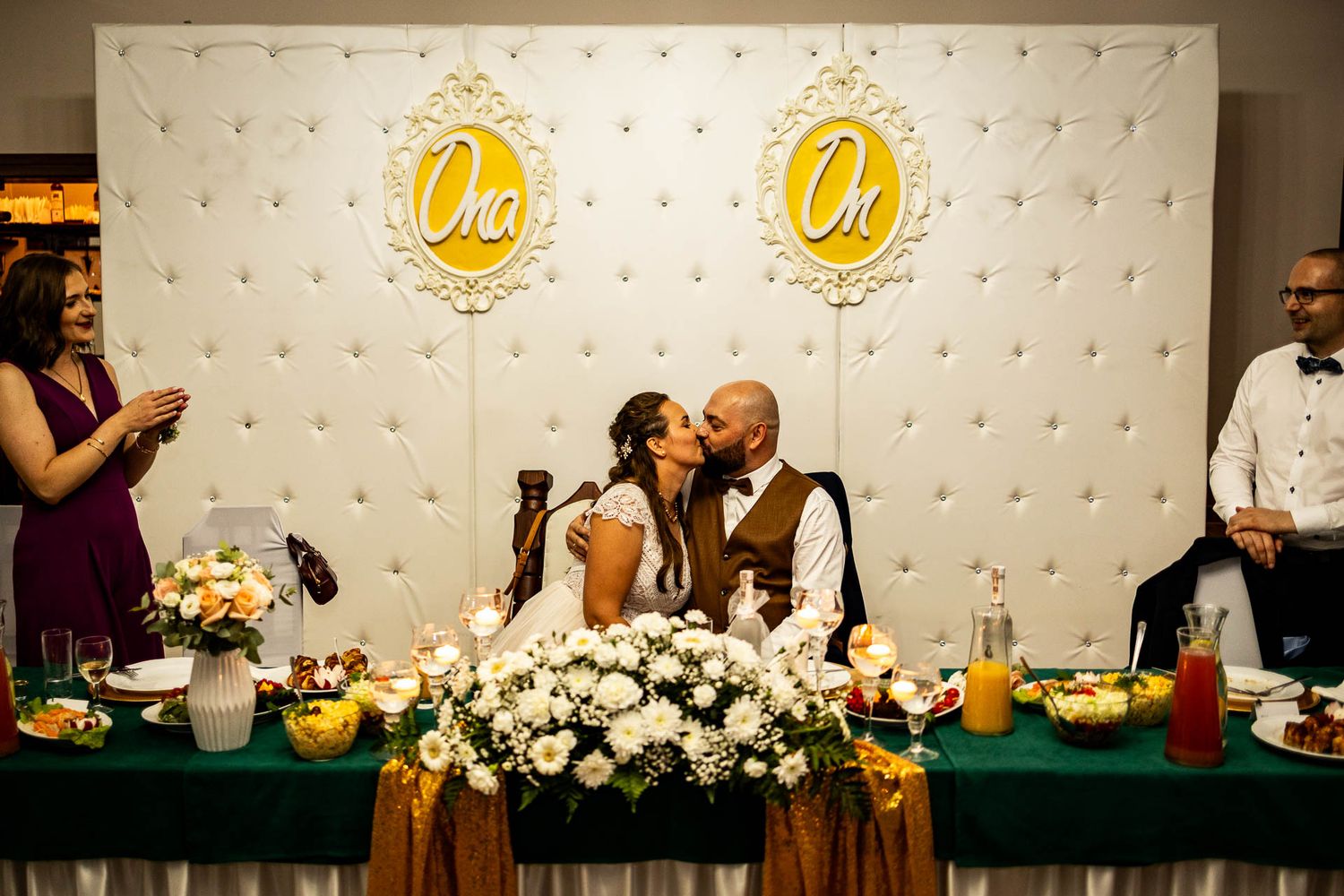 Elegant wedding reception setup with floral arrangements and decorative lighting against a branded backdrop.