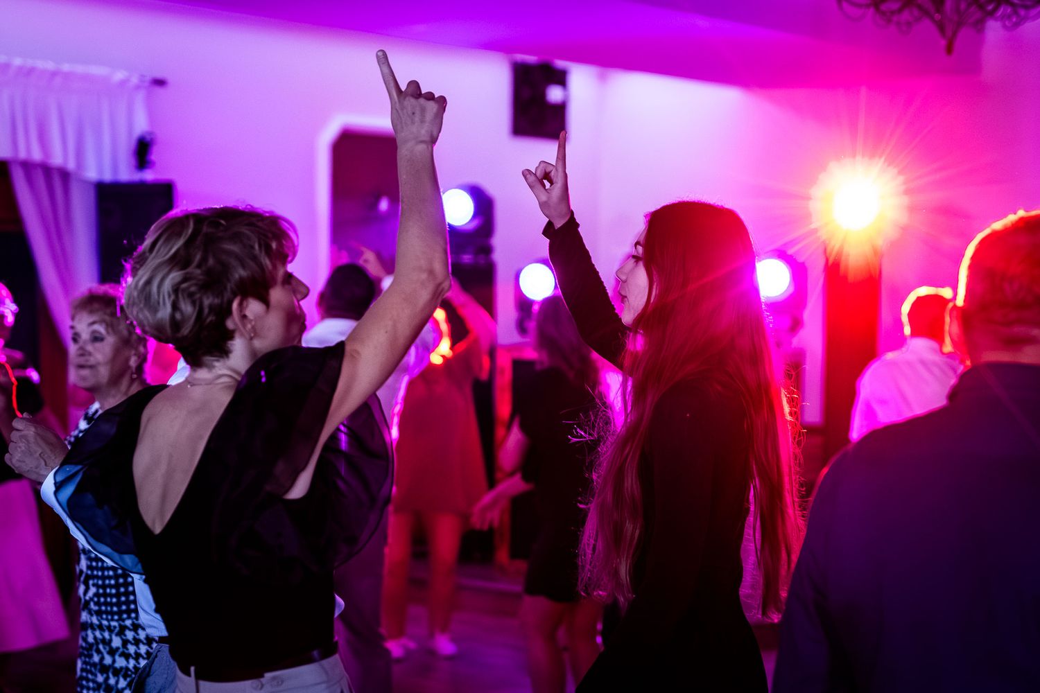 Dance floor illuminated with vibrant purple and pink lighting at a wedding reception.