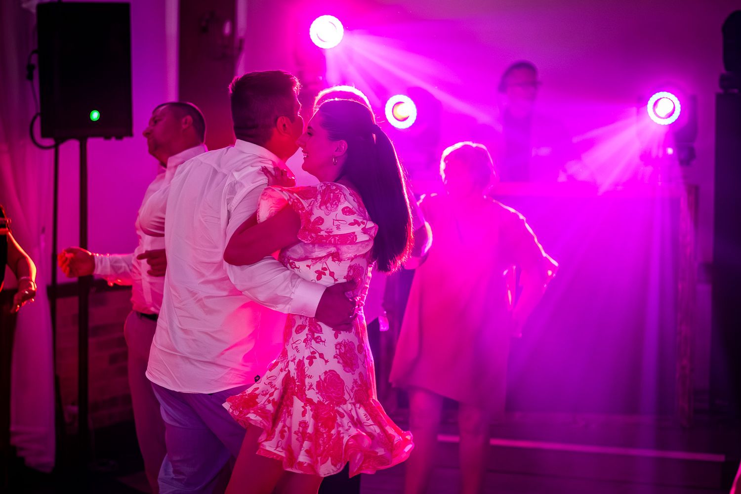 Wedding reception dance party with dramatic pink lighting effects.