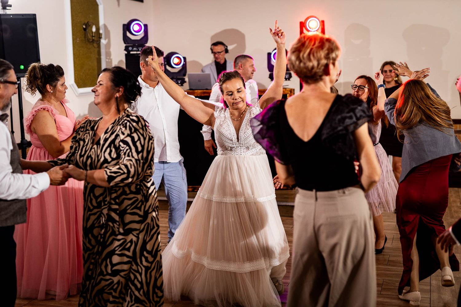 Wedding guests dancing and celebrating on a crowded reception dance floor.