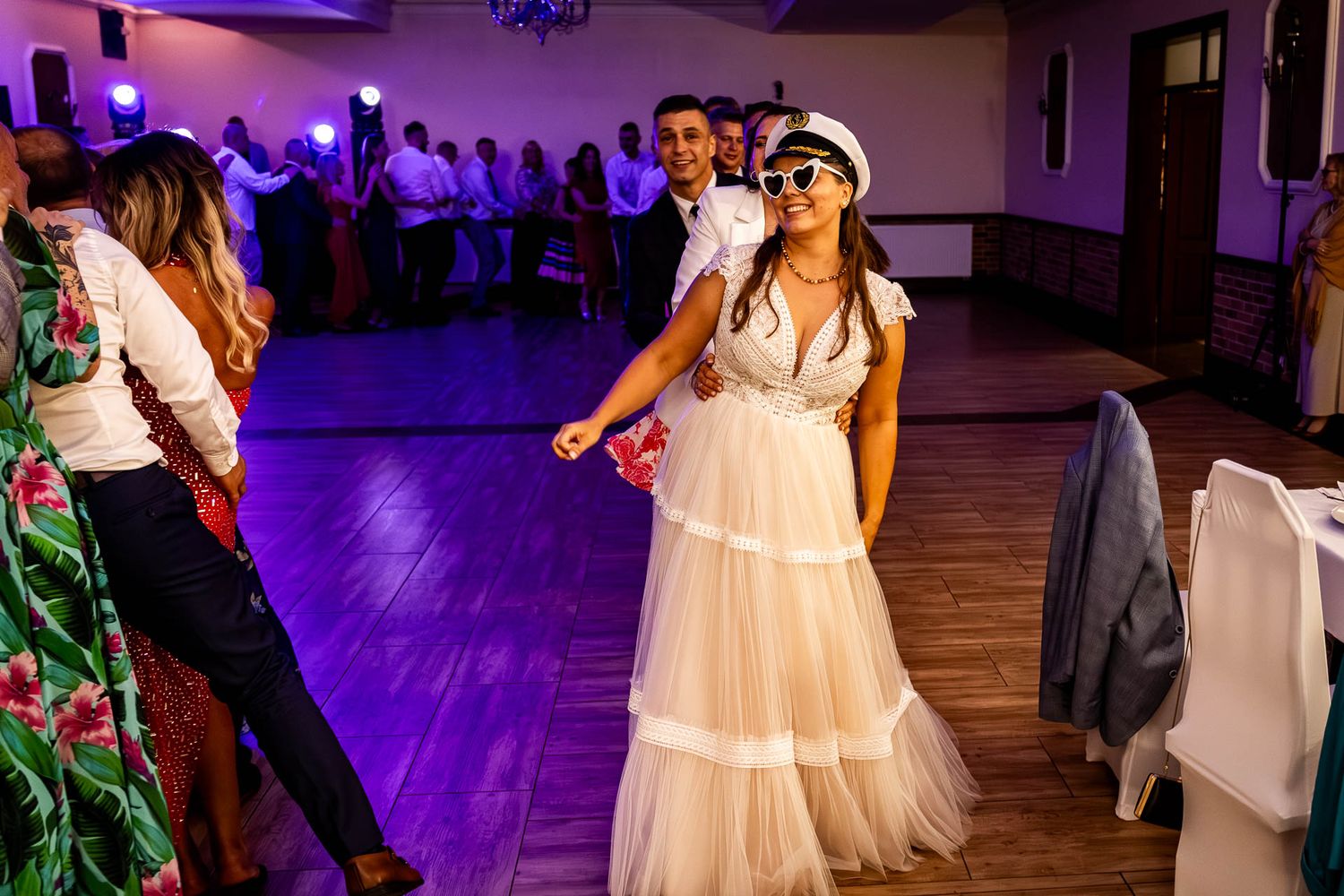 A dance party at a wedding reception with purple mood lighting and a flowing white dress.