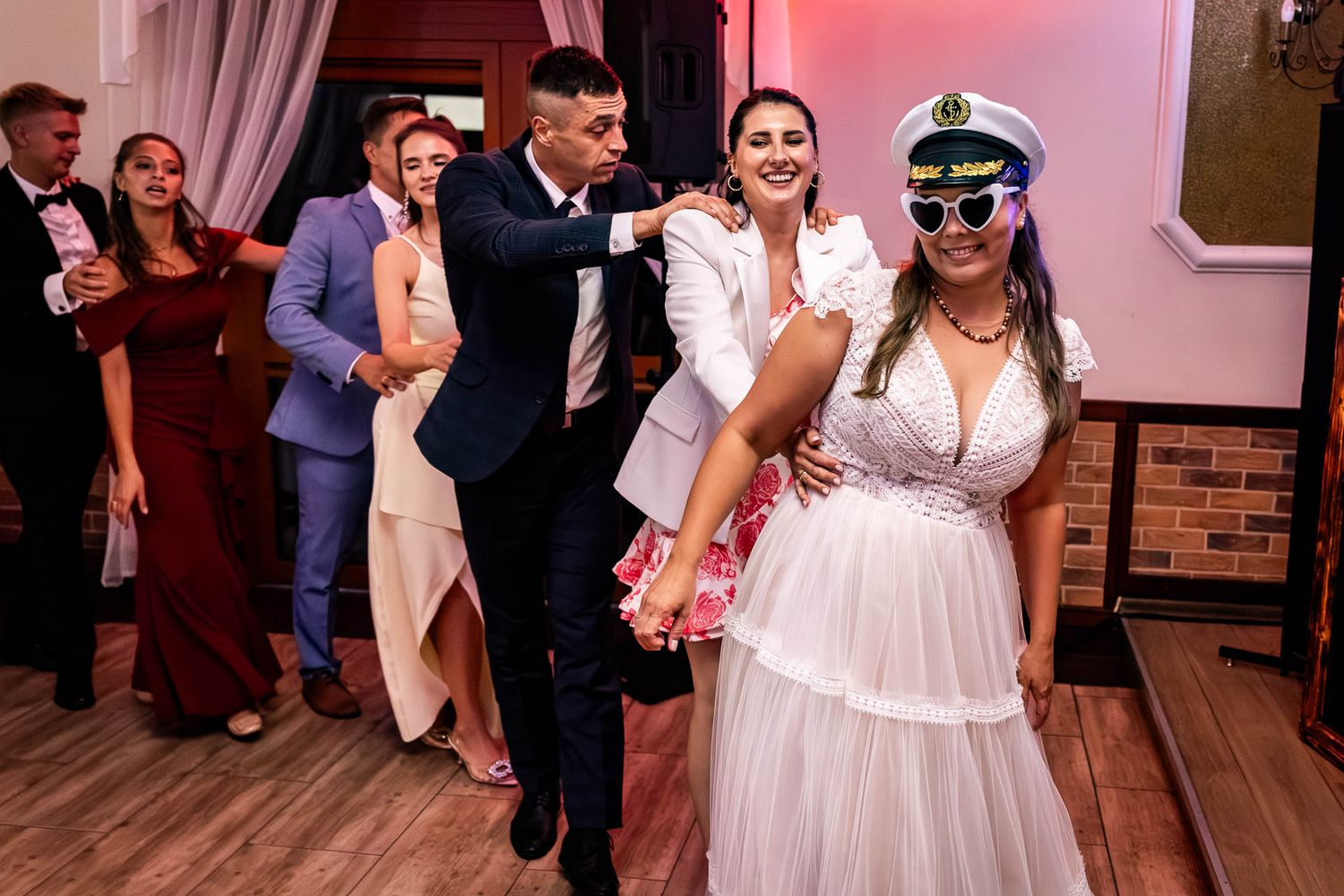 Wedding celebration on a dance floor with festive lighting and guests dancing.