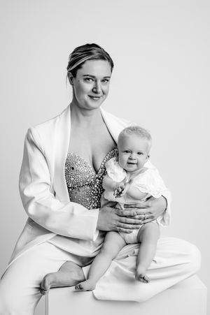 A series of black and white studio portraits showing a parent in a white blazer holding a baby in various poses.