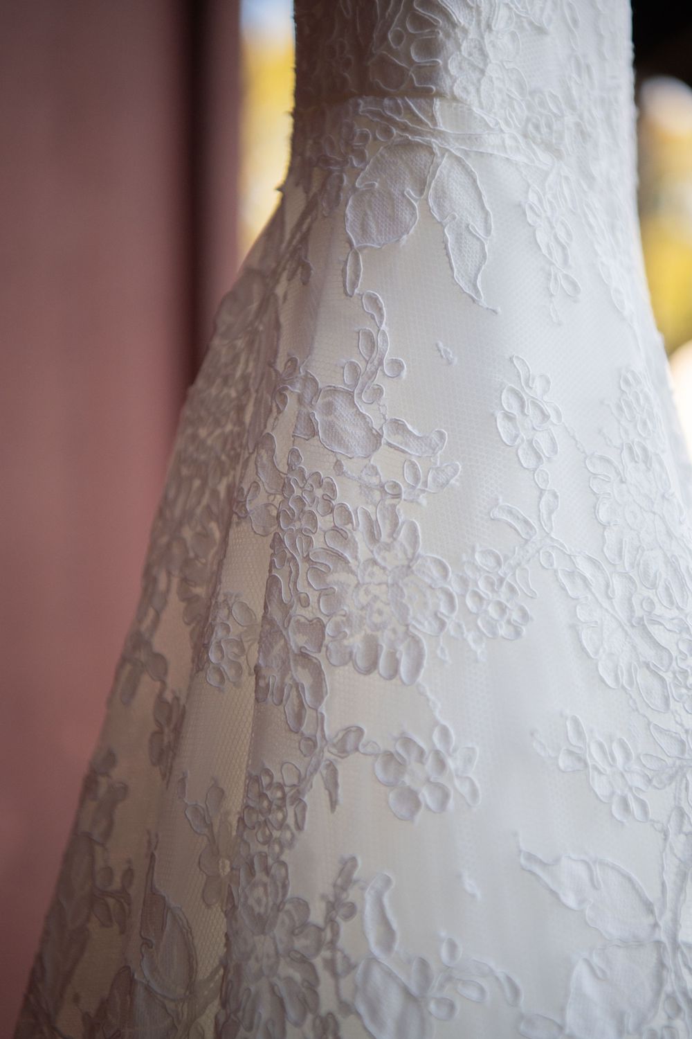 Close-up details of delicate white lace patterns on a wedding dress fabric.