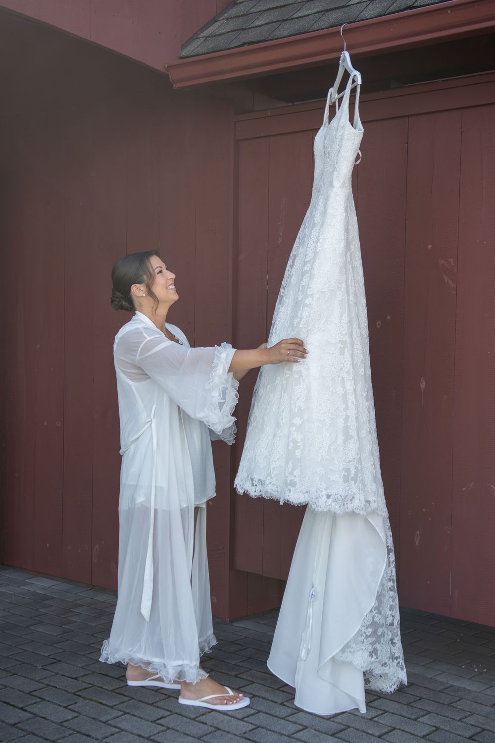 A white wedding dress being steamed and prepared against a red wall backdrop.
