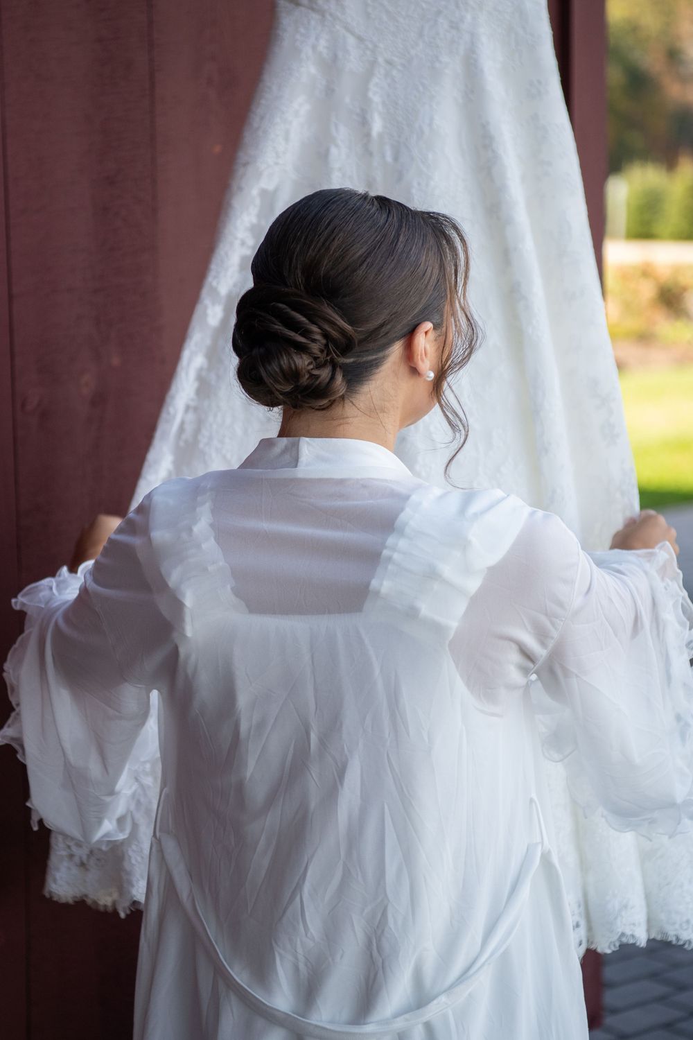 Back view of someone in white adjusting a hanging wedding dress.
