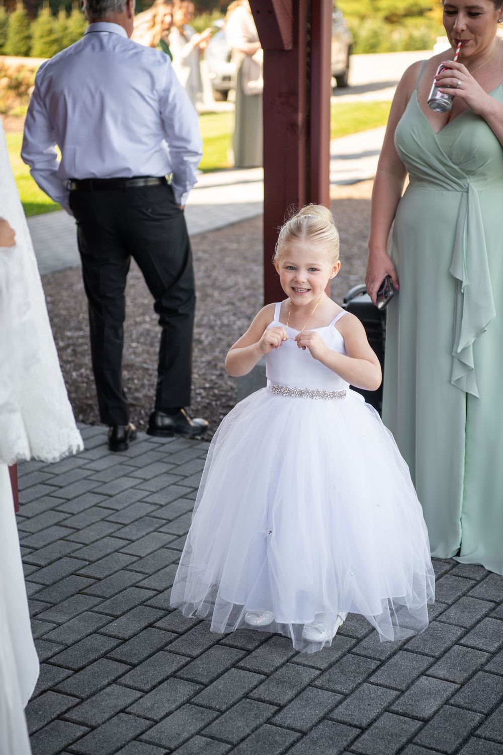 Two flower girls in white tulle dresses twirling on brick pavement.