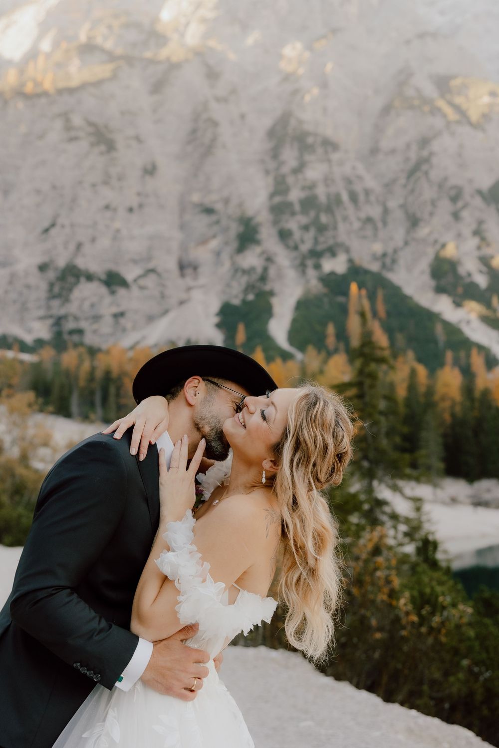 A romantic wedding couple shares intimate moments against a stunning mountain backdrop at sunset.