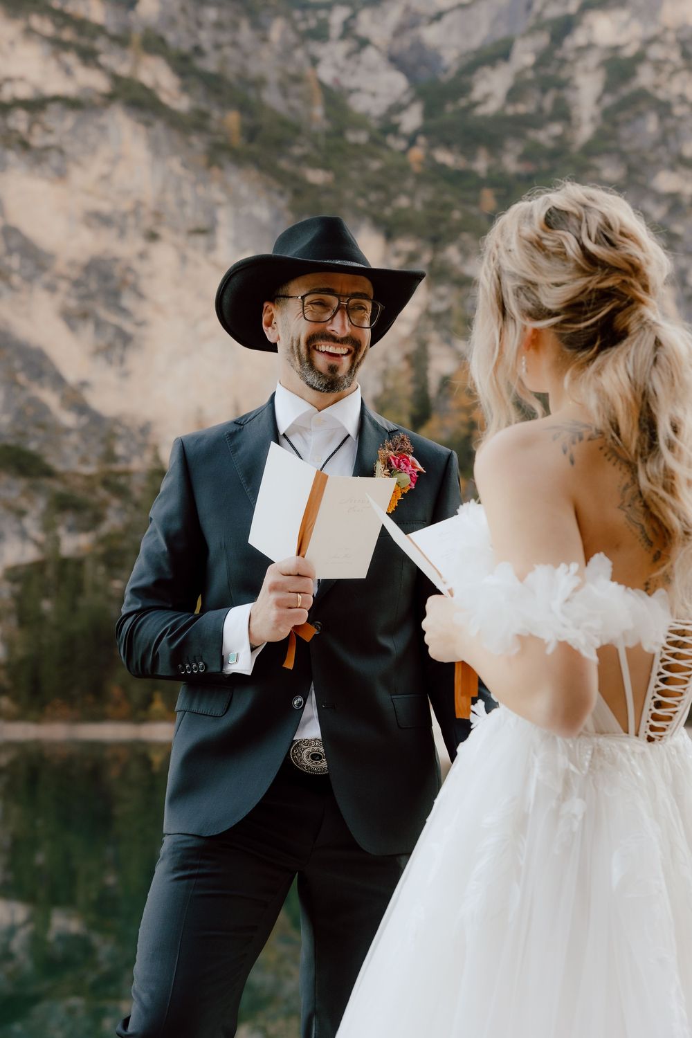 A couple exchanges vows during their outdoor mountain wedding ceremony beside a scenic lake.